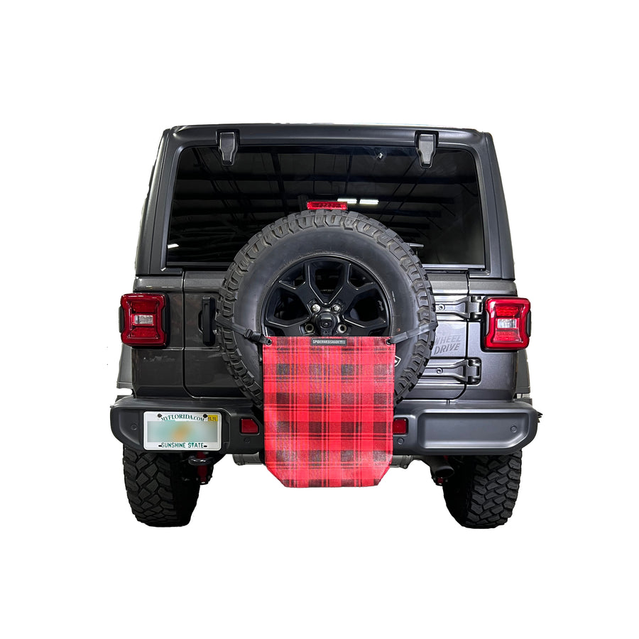 Beach bag with red and black buffalo plaid design on rear tire using strap to hold it up.
