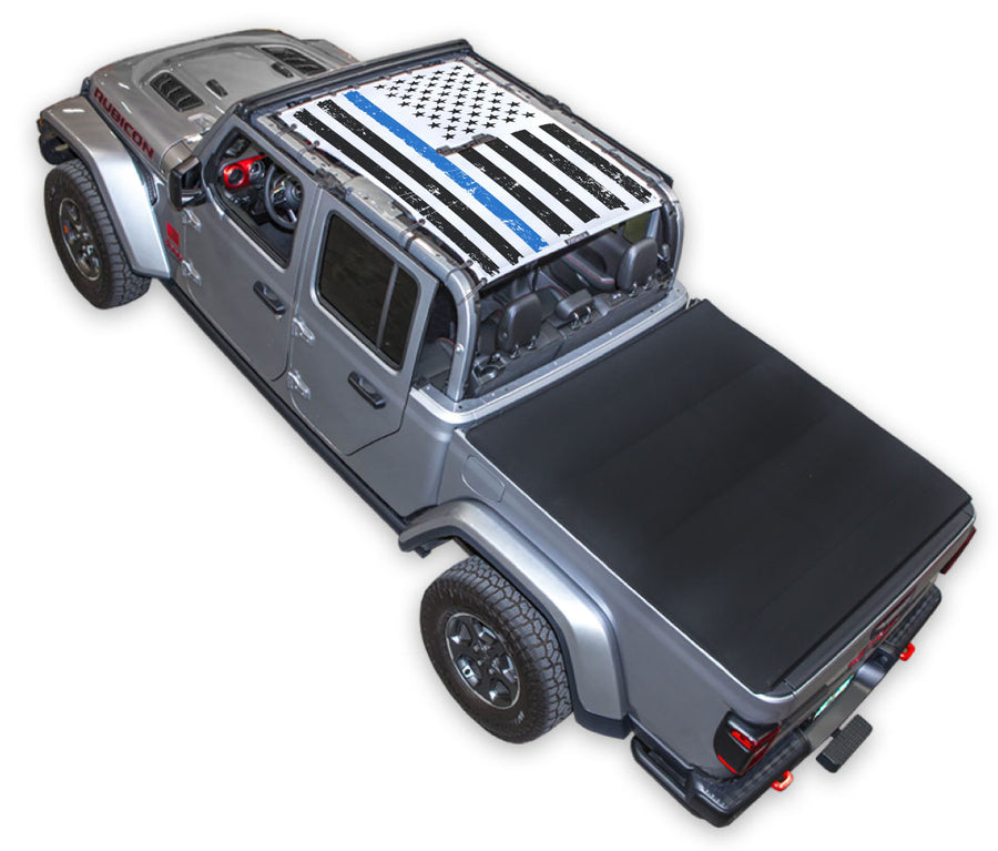 Silver Gladiator JT four door Jeep with Distressed Thin Blue Line tactical Flag white SPIDERWEBSHADE shade on top that covers front and rear passenger seats.
