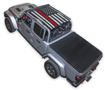 Silver Gladiator JT four door Jeep with Distressed Thin Red Line tactical Flag Black SPIDERWEBSHADE shade on top that covers front and rear passenger seats.