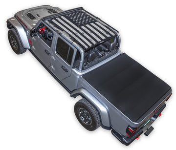 Silver Gladiator JT four door Jeep with Distressed tactical Flag Black SPIDERWEBSHADE shade on top that covers front and rear passenger seats.
