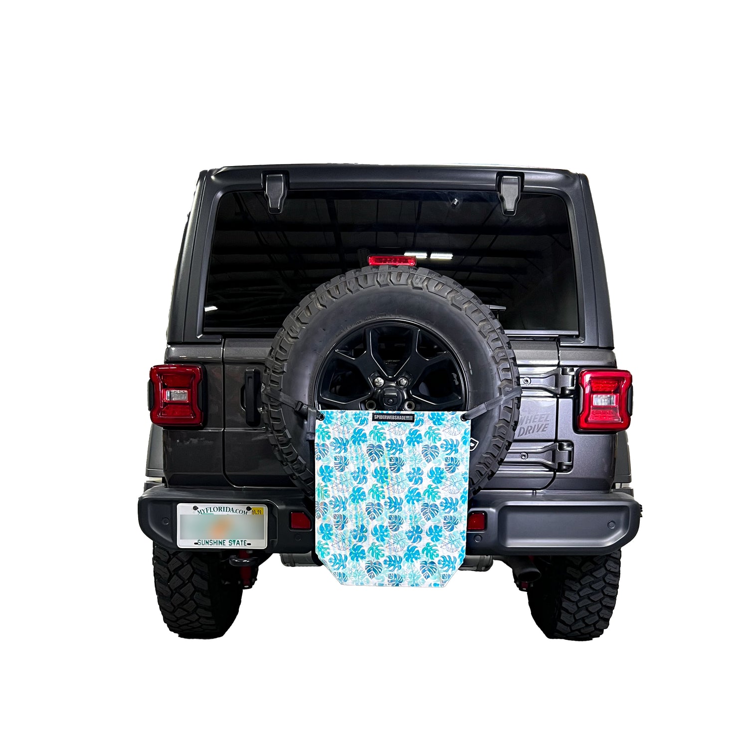 Beach bag with teal and blue Monstera Leafs on white mesh on rear tire using strap to hold it up