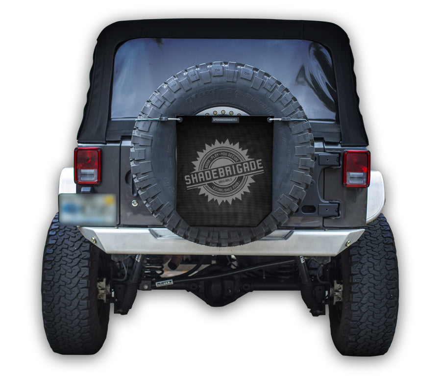 Jeep with Black Buggy Bag on rear tire with a Grey Shadebrigade logo in center of it being held up with a trail cord around tire.