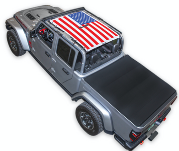 Silver Gladiator JT four door Jeep with American Flag design SPIDERWEBSHADE shade on top that covers front and rear passenger seats.